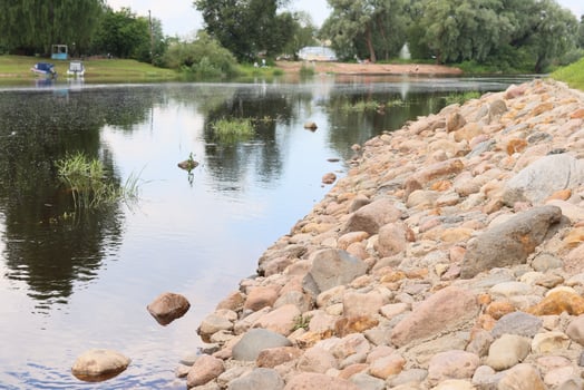 A Serene Riverscape encompassing a Charming Pebble Shore and Abundant Lush Greenery all around photo