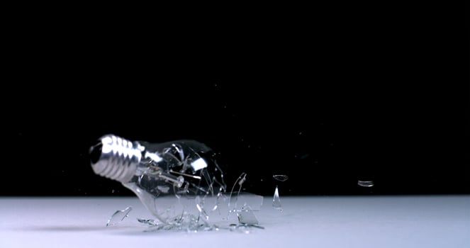 A broken light bulb on a table with a black background photo
