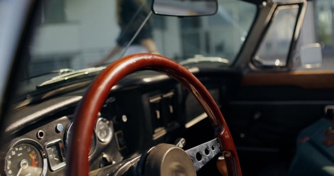 A steering wheel and dashboard in a classic car photo