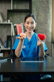 A cheerful healthcare worker in blue scrubs displays a brain model and heart symbol, emphasizing health and wellness. photo
