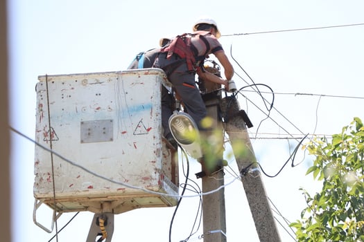 An Electrician Working on Power Lines from a Cherry Picker High Above the Ground Level photo