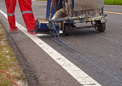 Road workers use hot-melt scribing machines to painting dividing line on asphalt road surface in the city. photo
