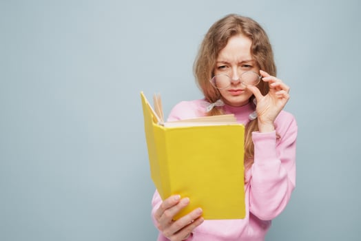 Woman in Glasses Struggling to Read Book with Poor Vision photo