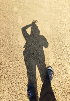 A person standing in the sand with their shadow photo