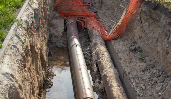 Close-up, repair of heating main, laying of large-diameter metal pipes in a trench, protective warning signs. photo