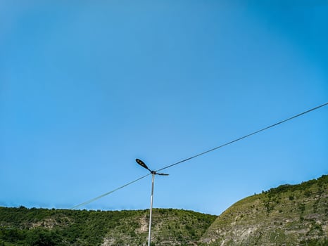 A tall pole with a light on top of it is standing in a field. The sky is clear and blue, and there are no clouds in sight. The scene is peaceful and serene photo