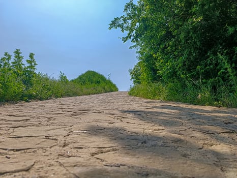 A dirt road with a hill in the background. The road is empty and the sky is clear photo