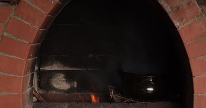 Clay pot placed inside rustic oven with vibrant flames growing steadily, showcasing traditional cooking techniques in an earthy environment that emanates warmth and comfort photo