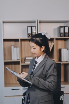 Asian female student in business suit writing on a clipboard photo
