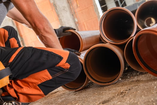 Worker Organizes Plastic Pipes at a Construction Site During Daylight Hours photo