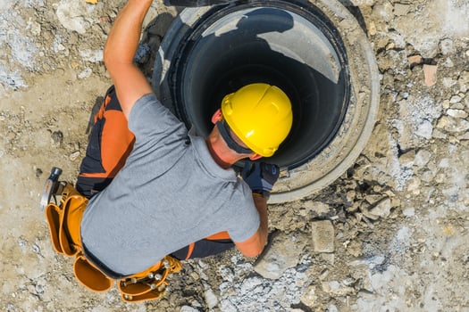 Construction Worker Repairing Sewer Line at Daytime in Urban Area photo