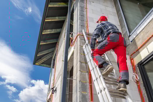 Worker Climbs Ladder to Inspect Construction Site Under Blue Sky With White Clouds photo