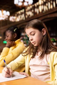Preteen scholars writing essays in a library in order to finish their homework assignments, descriptions to showcase creativity and imagination skills for the literature class. Educational growth. photo