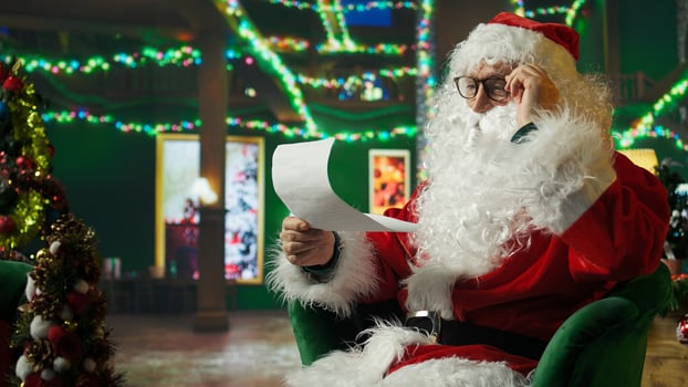 Senescent Santa Claus with bad eyesight struggling to read letters from kids, surrounded by holiday props. Old man adjusting glasses, trying to see children Christmas wish lists, camera A photo
