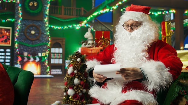 Smiling Santa Claus reading letters from kids, answering them, helping keep belief alive, showing thumbs up sign. Elderly person wearing Christmas costume doing positive agreement gesturing, camera A photo