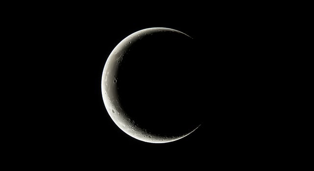 A crescent moon is seen in the dark sky photo