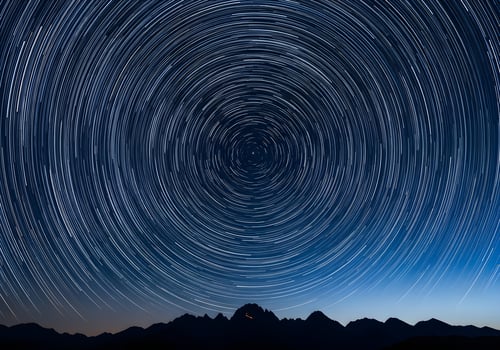 star trails over mountains in the night sky photo