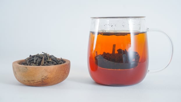 Tea in a teapot with a bowl of ground tea leaves isolated on white background photo