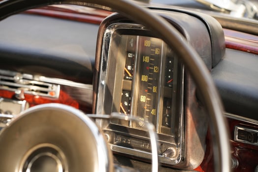 The dashboard of a vintage classic car features detailed analog gauges, a radio, and air vents in polished wood and chrome, offering a fresh yet luxurious look.bdh photo