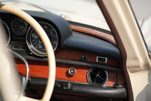 The dashboard of a vintage classic car features detailed analog gauges, a radio, and air vents in polished wood and chrome, offering a fresh yet luxurious look.bdg photo
