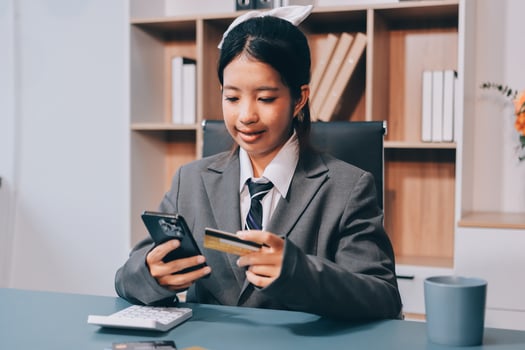 A woman in a business suit holding a cell phone and a credit card photo