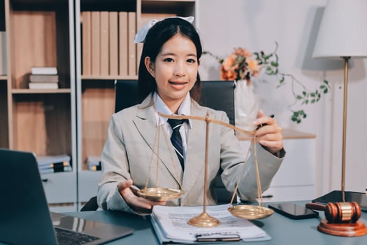 Asian female lawyer holding scales of justice in office photo