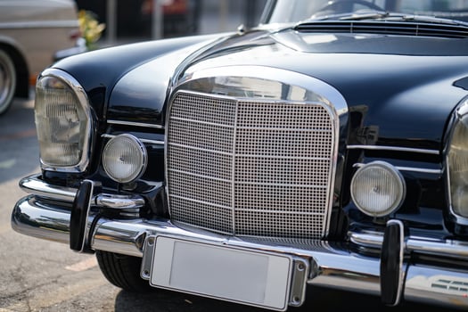 The round headlights and side turn signals on classic cars, framed in polished chrome, highlight the vintage style with old-fashioned lighting and curved fender details.ee photo