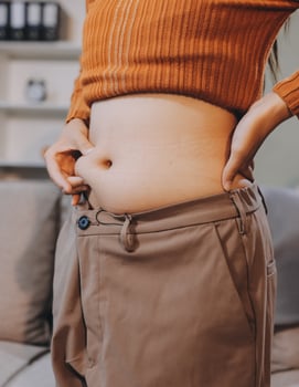 A woman with a belly showing off her pants photo