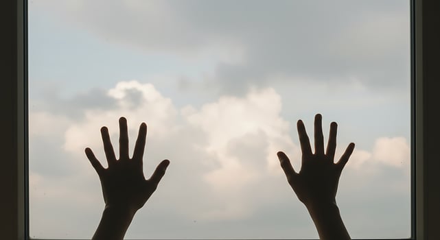Silhouetted Hands Reaching Toward Cloudy Sky Through Window photo
