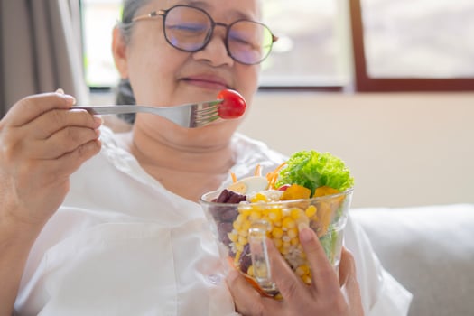 Shot of happy mature senior Asian woman eating healthy food at home. Retirement healthy food concept. photo