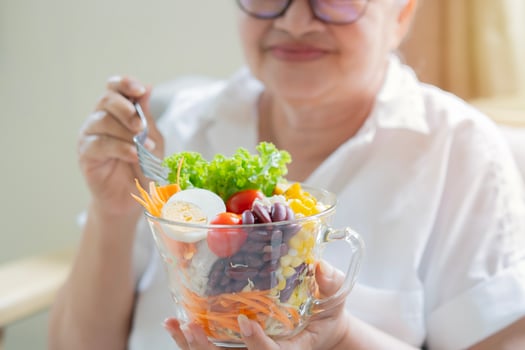 Senior woman ready to eat a salad of fresh and dried fruits. Breakfast or lunch time photo