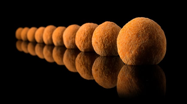 A Row of Orange Spheres Mirrored on a Black Surface. photo