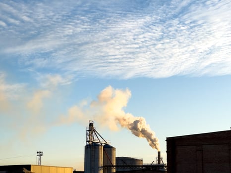 Smoke rises from a factory against a clear sky, highlighting the industrial landscape during the evening hours photo