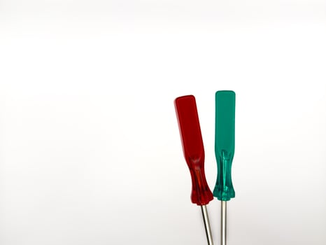 Two small plastic screwdrivers on a white background, red and green. copy space, flay lay photo