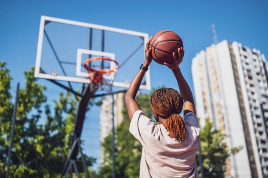 Young African American woman taking a basketball shot on an urban outdoor court during a sunny summer day. photo