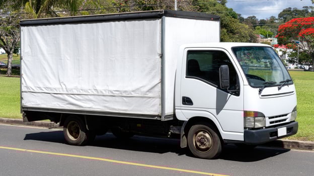 A white truck with a tarp covering it is parked on the side of the road photo