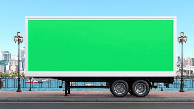 A green billboard on a truck in front of a city photo