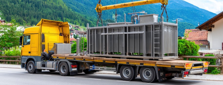 A truck carrying a large metal container on the back of a flatbed truck photo