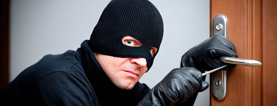 A burglar in a black mask and gloves is holding a key photo