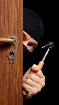 A burglar hiding behind a door with a hammer photo