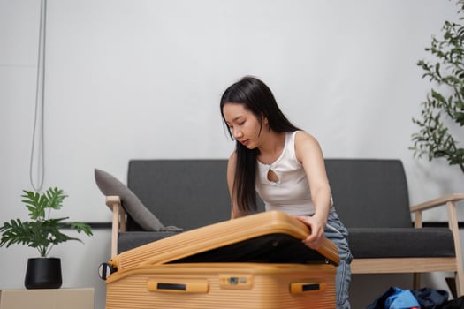 Young Woman Packing Suitcase for Travel Adventure in Modern Living Room Setting with Stylish Decor and Casual Clothing photo