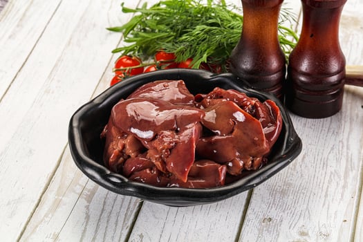 A bowl of meat and a bottle of ketchup on a table photo