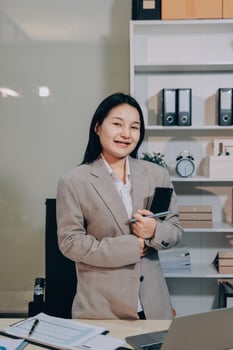 Asian business woman standing in office with laptop and phone photo