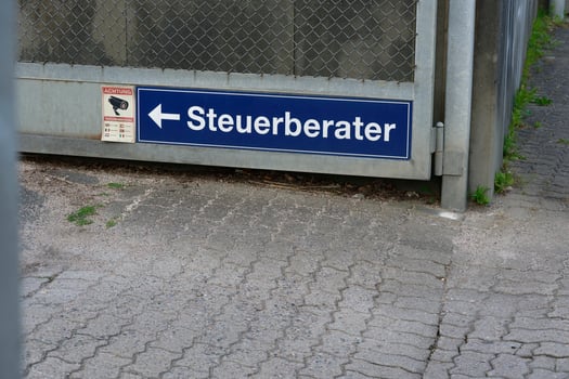 German sign for a tax consultant office with directional arrow and a reference to surveillance photo