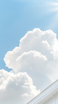 Majestic white cumulus clouds float gracefully across a brilliant azure sky, complemented by the clean architectural lines of a modern building facade. photo