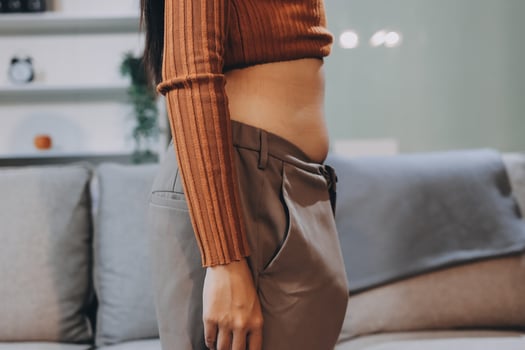 A woman in a brown sweater and pants standing on a couch photo