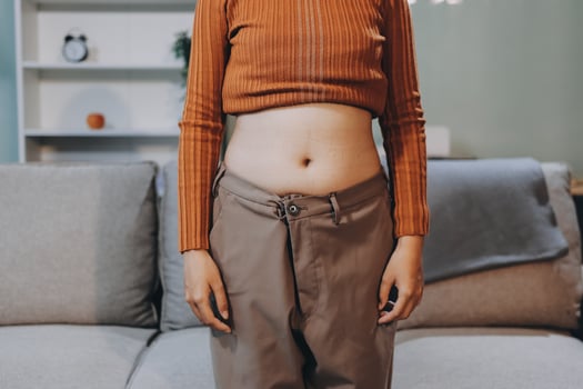 A woman in a brown pantsuit standing in front of a couch photo