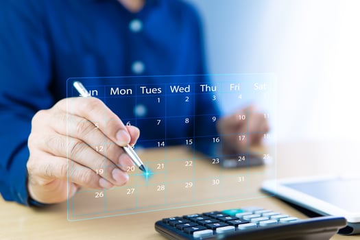 Virtual calendar and calculator on desk calculate income and expenses for each month. Month has 31 days, Sunday to Saturday. Male accountant uses digital pen to analyze details of items to plan work. photo