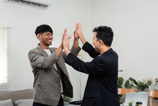 Teamwork and Business Success. Two men high-fiving in a modern office, celebrating their achievements and collaborative efforts. photo