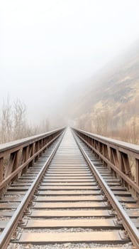 Misty railway bridge extends into the vanishing fog, a serene and atmospheric journey through a desolate mountain landscape. Captivating endless tracks. photo